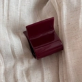 Detail view of small burgundy acetate square hair claw clip on soft beige fabric background - Burgundy
