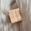 Detail of small tortoise shell acetate hair claw clip on neutral textured linen fabric - Off White
