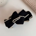 Detailed close-up of a black faux suede bow banana clip with elegant white stitching accents - Mousse Black
