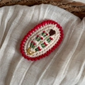 Détail macro d'une pince à cheveux au crochet rouge et blanc tricotée main avec broderie cœur - Bord Rouge Beige
