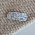 Close-up of black and white marble acetate hair clip on beige knit background - Cracked White