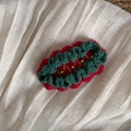 Détail d'une pince à cheveux tricotée rouge et verte avec perles dorées sur lin - Rouge avec Dentelle Verte