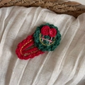 Vue détaillée de la pince à cheveux couronne de Noël tricotée à la main avec petits nœuds rouges - Disque Vert Nœud Rouge