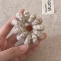 Gedetailleerd overzicht van beige pluche spiraal haarelastiek met een zachte gebreide textuur - Beige Abrikoos