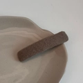 Vue détaillée de la pince à cheveux en tricot marron foncé sur un plateau sobre - Abricot Lacté