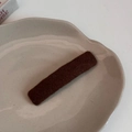 Détail d'une pince à cheveux rectangulaire en tissu marron sur un plat beige - Marron