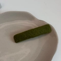 Gros plan sur la barrette à cheveux tricotée vert olive avec texture tissée sur plateau - Vert