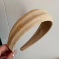 Detalle de diadema de terciopelo beige con textura tejida y etiqueta dorada - Beige