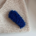 Detailierte Textur der dunkelblauen Teddy-Fleece-Haarspange auf beigem Strick - Blau