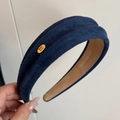 Dettaglio del cerchietto in velluto blu navy con trama pieghettata e targhetta dorata - Blu