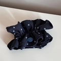 Detailaufnahme eines schwarzen gepunkteten Haargummis mit einem blauen Dekoknopf - Marineblau Punktiert Knopf