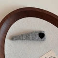 Close-up of grey knitted triangle hair clip with a black velvet heart on wood base - Light Gray
