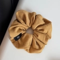Detailansicht des gelben Strick-Scrunchie mit einem schwarzen Schleifen-Etikett - Gelb