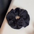 Detail of grey knitted hair scrunchie with soft fabric texture and bow logo tag - Black