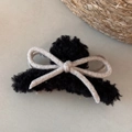 Detail of black faux lamb wool hair claw with a minimalist woven beige bow tie accessory - Black