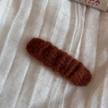 Detail shot of a dark brown knitted hair clip with rich texture on cream fabric - BB Clips / Red