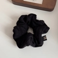 Detail view of black knitted scrunchie with Made in Korea tag on a white table - Hollow Knit Black