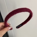 Detailed shot of handmade label on burgundy knitted headband with soft plush texture - Red