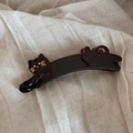 Detail of a shiny black resin banana hair clip featuring a cute cat design with gold whiskers - Dark Coffee