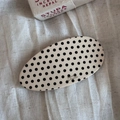 Close-up of an oval acetate hair barrette with a classic cream and black polka dot pattern - White Polka Dot