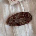Detailed close-up of a marbled acetate barrette clip on a soft white linen background - Reddish Brown Marble