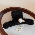 Detailed view of a black fuzzy plush hair claw clip with large pearl and gold logo coin - Black
