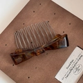 Close-up of tortoise shell pattern acetate bow hair comb with handmade logo detail - Blue Brown
