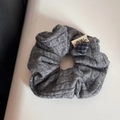 Dettaglio macro dell'elastico in maglia grigia con trecce e piccolo ciondolo a cuore - Scrunchie in Maglia - Grigio