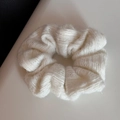 Close-up of soft white knitted scrunchie with warm wool texture and woven details - White