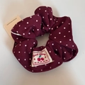 Detail view of burgundy polka dot scrunchie with sweet cherry fabric label and high elasticity - Red Polka Dot Scrunchie