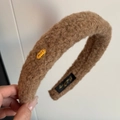 Detailed view of plush camel faux fur headband with a golden LOVE metal emblem - Light Coffee