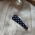 Detailed view of the black and white polka dot fabric triangle hair clip on beige cloth - Polka Dot Triangle Clip / Blue