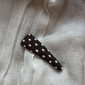 Close-up of brown knitted triangle BB clip with white polka dots on linen fabric - Polka Dot Triangle Clip / Brown