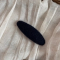 Primer plano de pasador de pelo ovalado negro minimalista sobre textura de tela de lino - Estilo Ovalado Azul