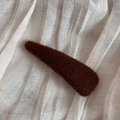 Primer plano de una horquilla de fieltro marrón en forma de gota sobre tela beige - Estilo Triángulo Café Oscuro