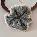 Detailed close-up of knitted scrunchie texture with cream tassels and fashion label - Fuzzy Edge Snowflake Knit Gray Scrunchie