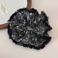 Detail of a large black and white tweed scrunchie with fringe edges and fashion label - Fuzzy Edge Snowflake Knit Black Scrunchie