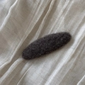 Close-up of a charcoal grey felt hair clip on a soft white linen fabric background - Oval / Dark Khaki