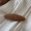Detail view of oval brown felt hair clip on white fabric with natural rustic elements - Oval / Yellow Coffee