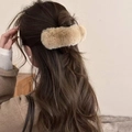 Détail d'une pince à cheveux en fourrure de vison kaki portée sur de longs cheveux ondulés - Couleur Thé au Lait