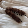 Nahaufnahme der flauschigen braunen Bananen-Haarklammer auf weichem beigem Stoff - Dunkler Leopard