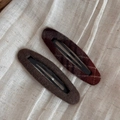 Close-up of two wool fabric snap hair clips in solid dark brown and red plaid pattern - Plaid Brown Hollow Oval BB Pair Clips