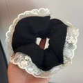 Close-up of black knit scrunchie with white lace trim and intricate floral details - Knitted Lace Trim (FQ881036) / Black