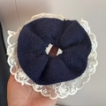 Detail of oversized navy knit scrunchie with delicate white lace trim held by hand - Knitted Lace Trim (FQ881036) / Blue