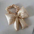 Detalle del coletero de satén oro champán con un gran lazo acolchado de seda elegante - Beige