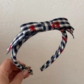 Detail von blau kariertem Haarreif mit roten Schleifenstickereien und Knoten - Schwarz-weiß karierte Schleife
