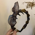 Detail eines Haarreifens mit olivgrüner Satinschleife, Anti-Rutsch-Zähnen und Blumenstoff - Braun