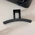 Close-up of curved black hair claw clip with white polka dots on a minimalist desk - Black (Large Claw)