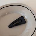 Détail de la pince à cheveux triangle en cuir PU noir avec coutures sur assiette beige - Grand Triangle / Noir