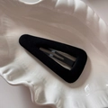 Close-up of a black flocked triangle hair clip on a white decorative shell plate - Triangle-Black